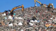 Seorang pemulung perempuan menyusuri tumpukan sampah di TPA Cipayung Depok dengan karung dan alat penjepit sampah