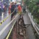 Petugas Satgas memasang terpal biru dan rambu peringatan di lokasi trotoar Jalan Raya Bogor Depok yang longsor akibat hujan deras.